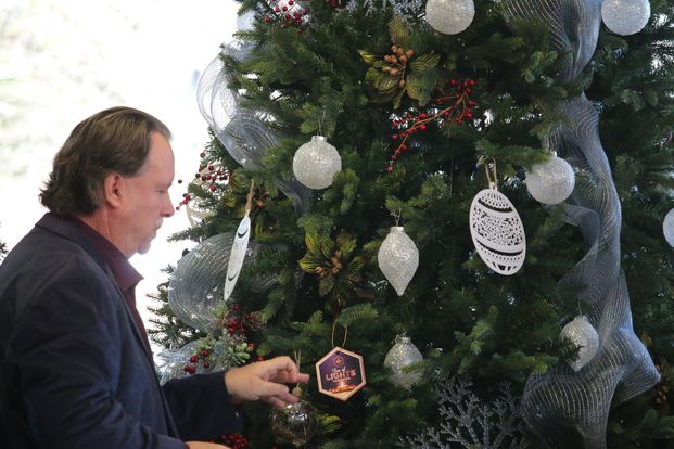 Person placing an ornament on a christmas tree